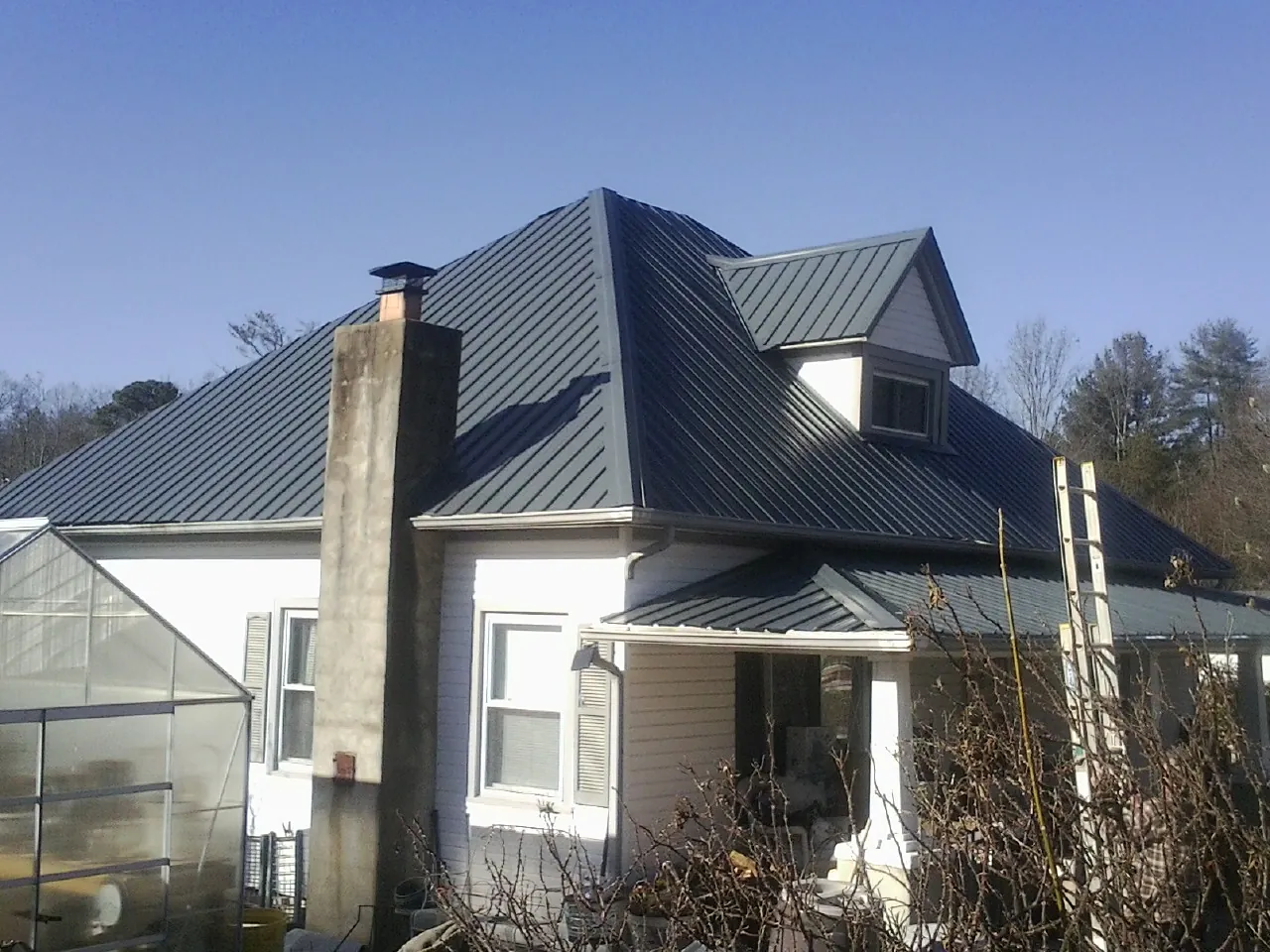 Dark blue standing seam metal roof on a white farmhouse with dormer — Slate & Tile Roof Repair by Roofing Brothers in Fairview Heights