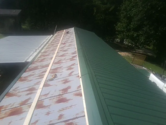 Old rusted panels beside newly installed green metal roofing — Wind Damage Roof Repair by Roofing Brothers in Fairview Heights