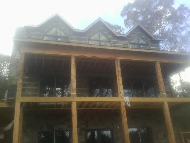 Dormers and porch framing on a large log home under construction — Roof Coating work by our crew in Fairview Heights