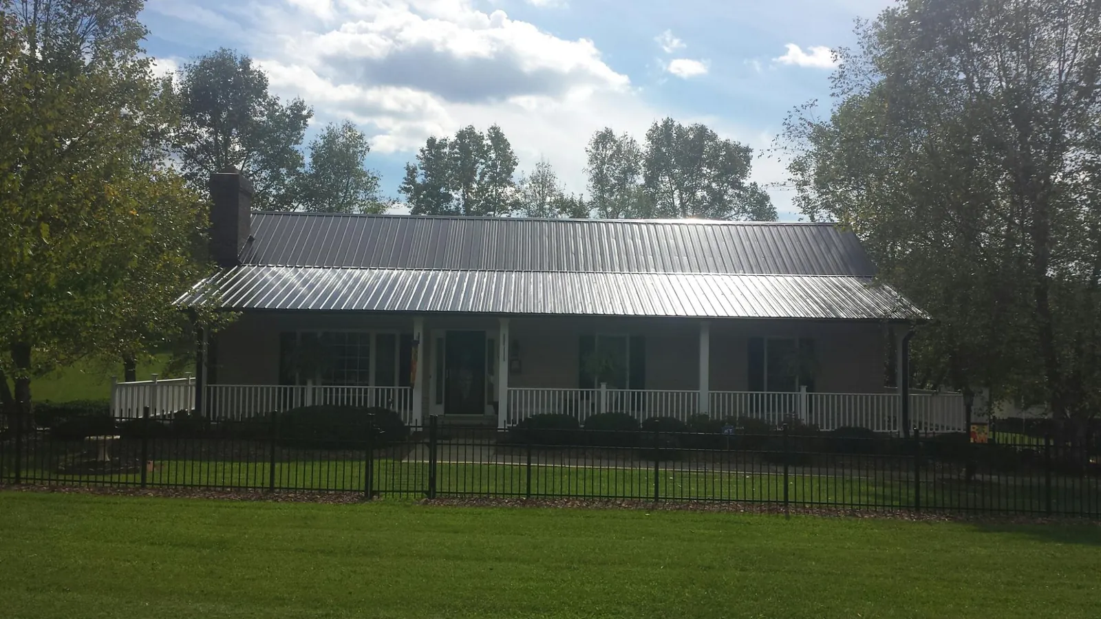 Gray metal roof on a brick ranch with a full width front porch — Gutter Guard Installation work by our crew in Fairview Heights