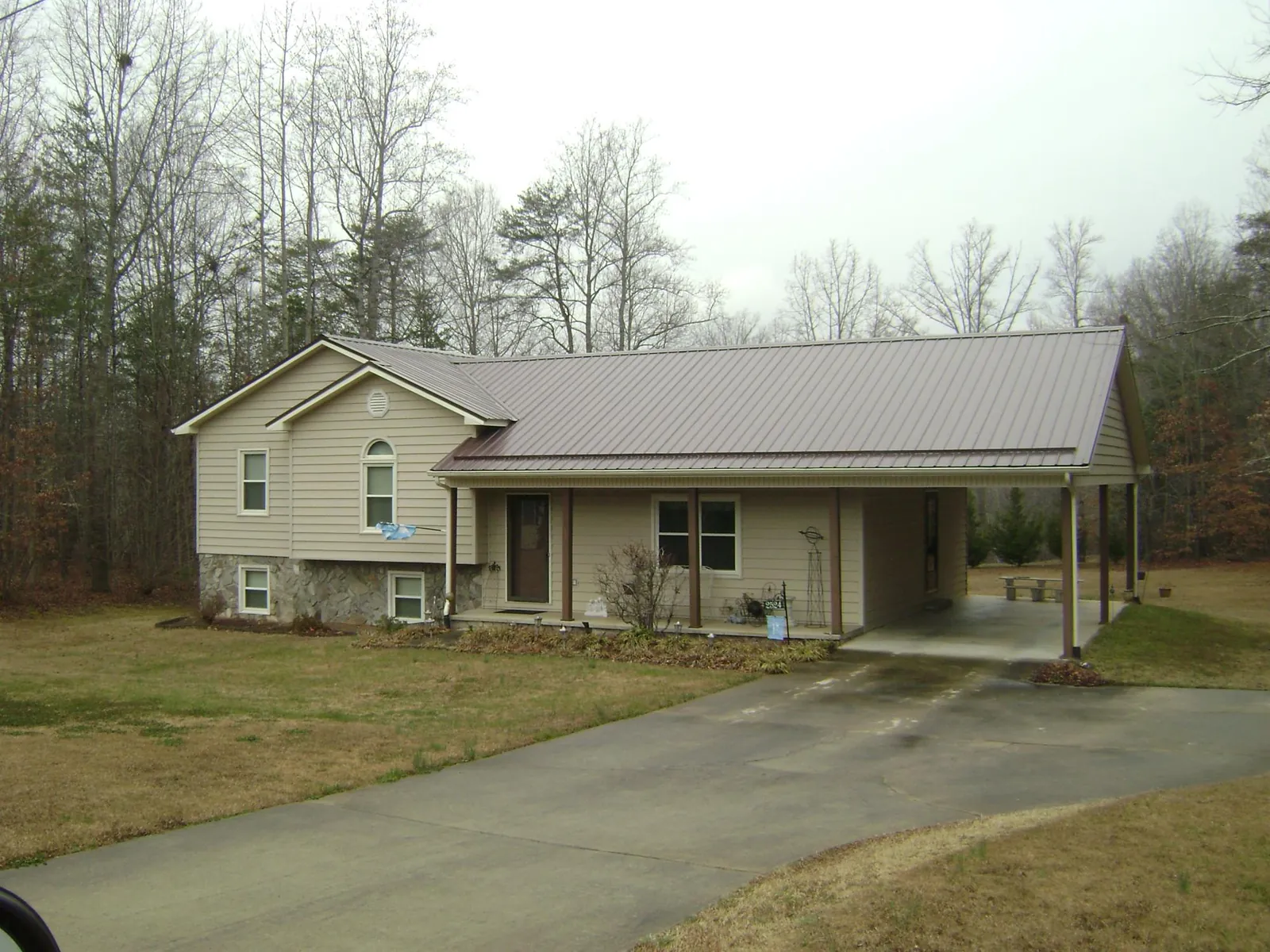 Brown metal roof on a tan split level home with an attached carport in Fairview Heights