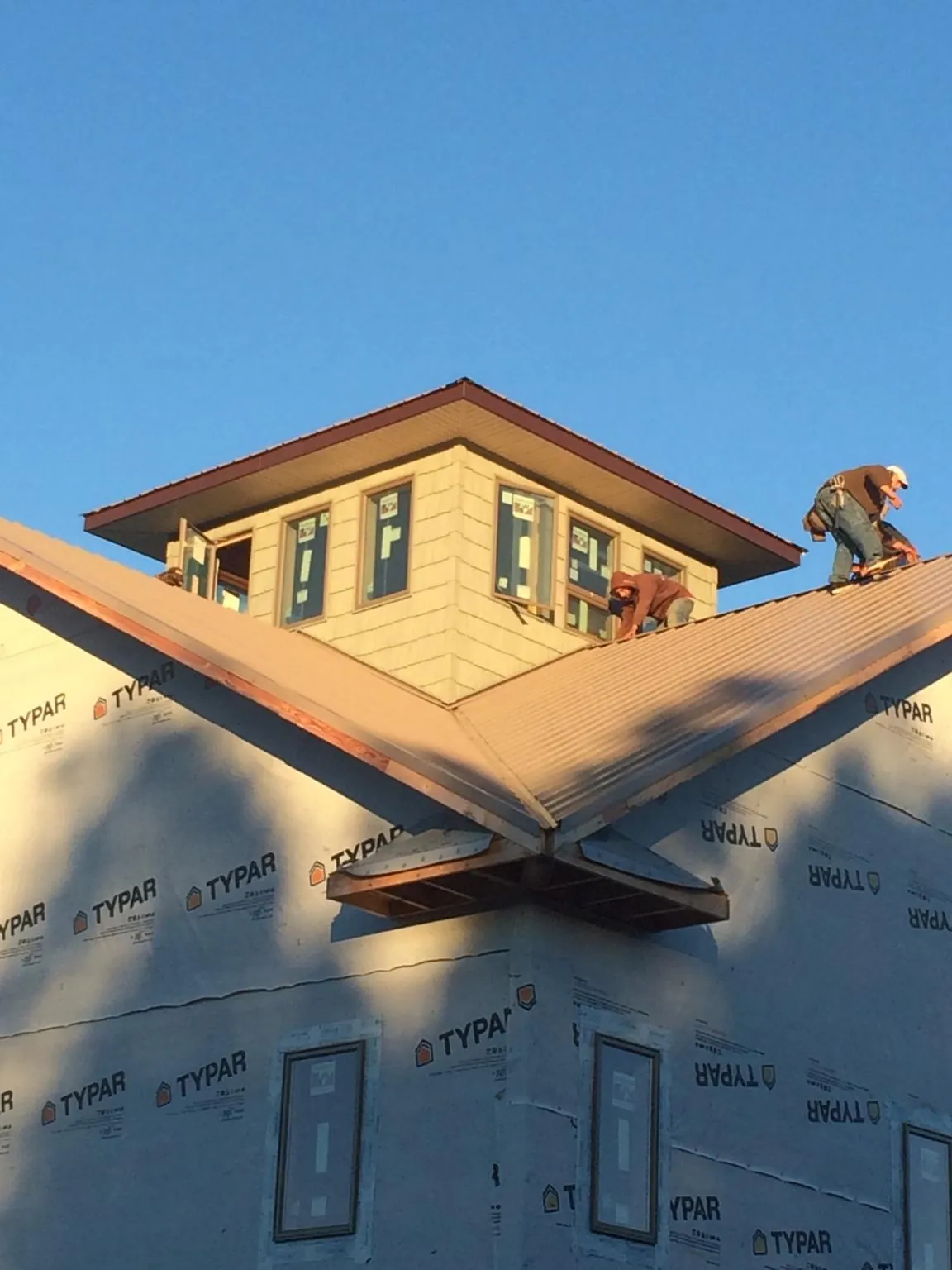 Roofers working around a rooftop cupola on a new metal roof at sunset — Roof Waterproofing in Fairview Heights by Roofing Brothers